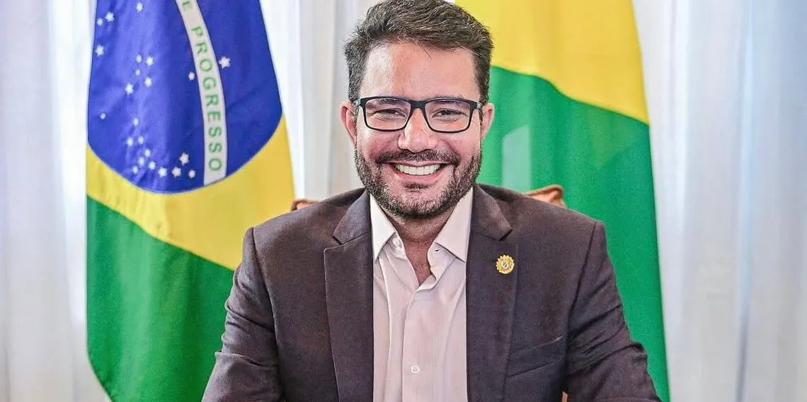 Gladson Cameli em primeiro plano e ao fundo uma bandeira do Brasil e uma bandeira do Acre